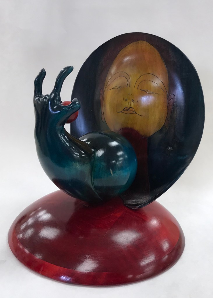 Turned and carved sculpture in wood depicting a sublime face of Virgo  as she is offered the strawberry moon by Mother Earth 